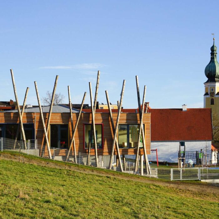 Kinder spielen auf einem Huegel mit Holzpfaehlen im Kindergarten Taennsberg