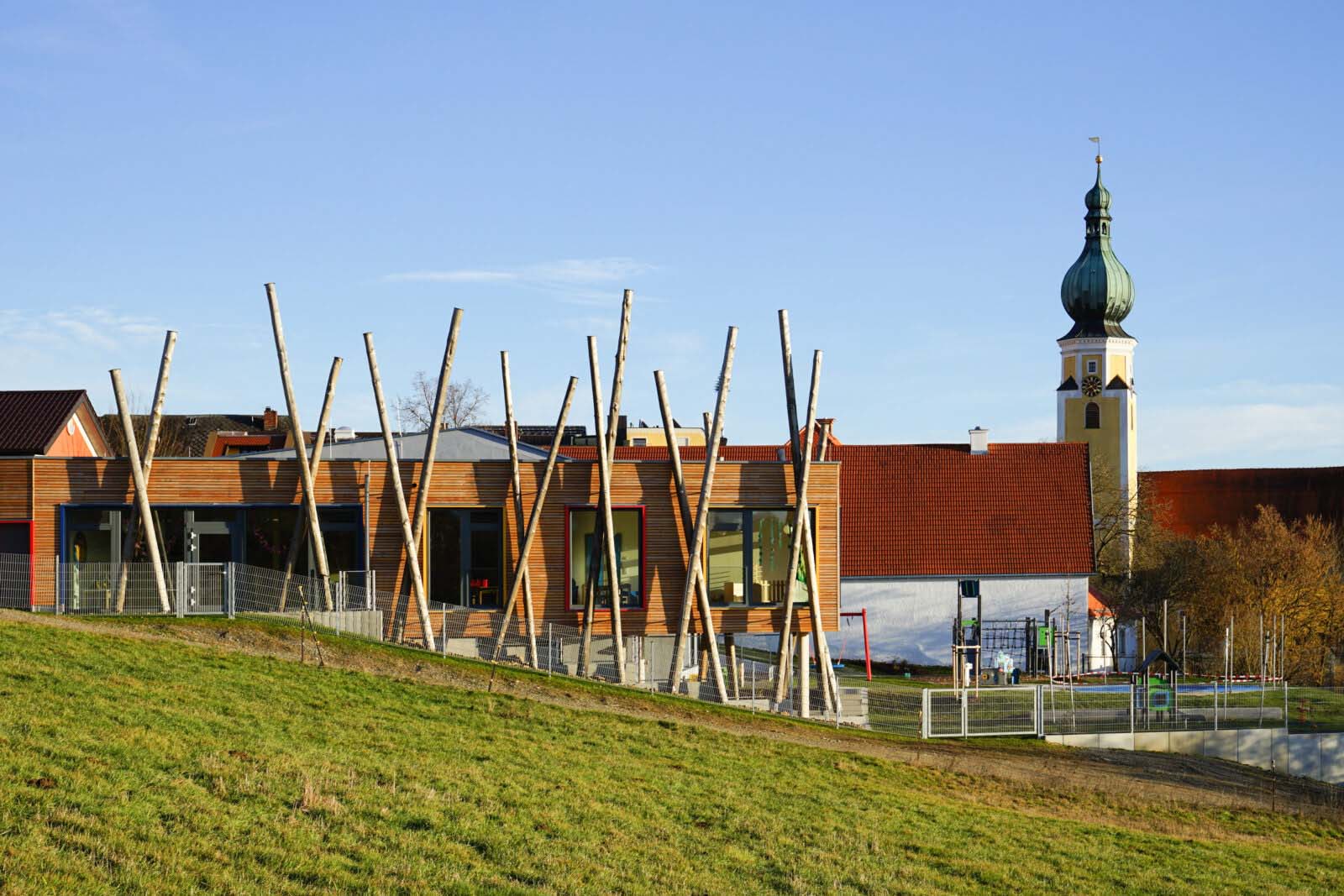 Kinder spielen auf einem Huegel mit Holzpfaehlen im Kindergarten Taennsberg